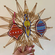 Decorative 3D Goldwork embroidered ornament  held by a hand against a neutral background